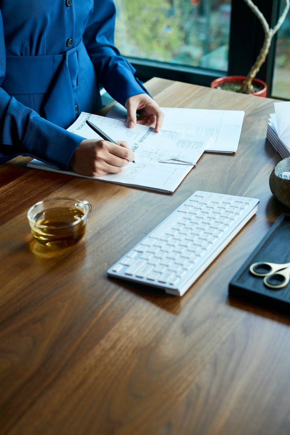 Person writing with a pen on technical drawings at a desk.