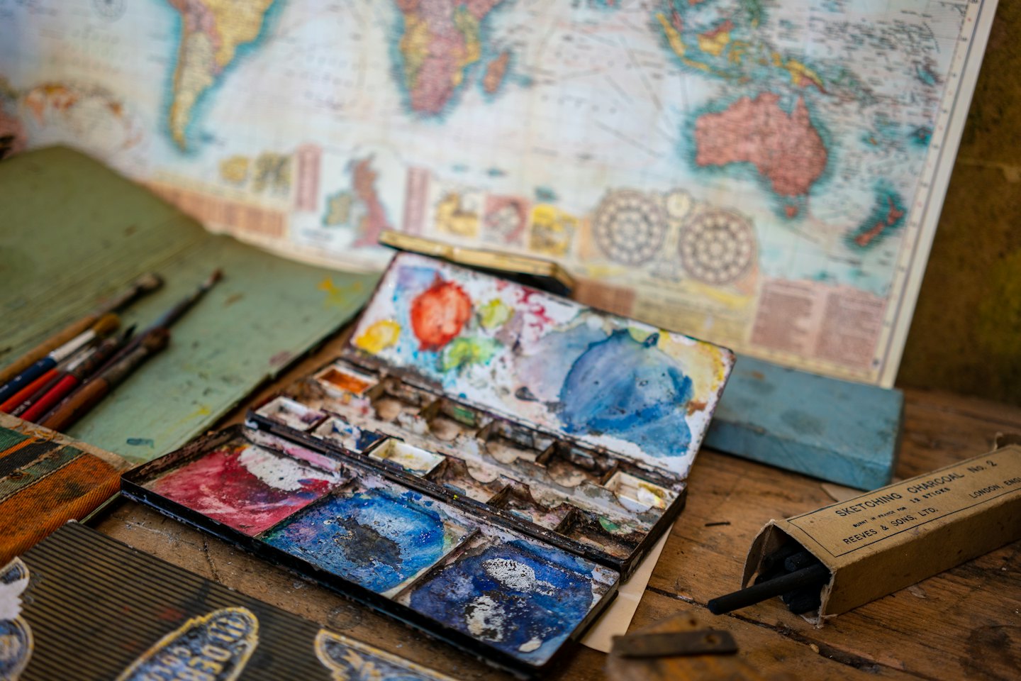 Watercolor paint palette and brushes on a wooden table.